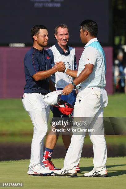 Xander Schauffele of Team United States shakes hands with Hideki Matsuyama of Team Japan as caddie John McLaren looks on after Schauffele putted on...