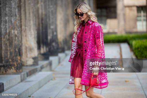 Mandy Bork is seen wearing Dior dress in red, rain coat with print, red Lady Dior micro bag and sandals Dior, Bottega Veneta sunglasses on July 31,...