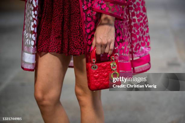 Mandy Bork is seen wearing Dior dress in red, rain coat with print, red Lady Dior micro bag and sandals Dior, Bottega Veneta sunglasses on July 31,...