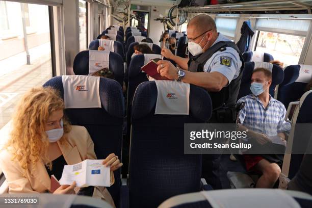 Members of Germany's federal police check whether passengers have proof of vaccination or a recent negative Covid test on a train arriving from...