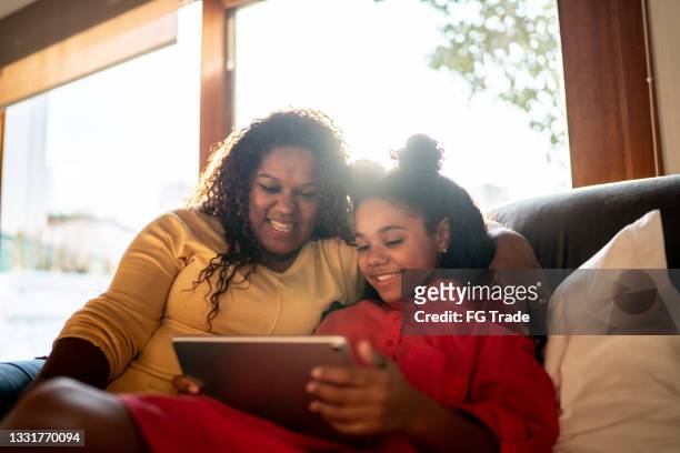 mother and daughter using digital tablet at home - mother happy reading tablet stock pictures, royalty-free photos & images