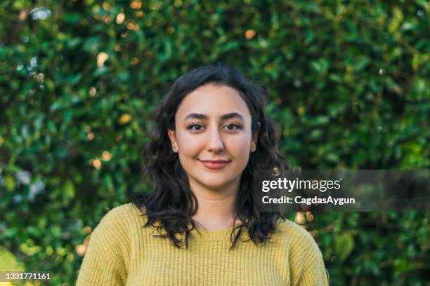 smiling young woman on the background of lush leaves - turkish ethnicity stock pictures, royalty-free photos & images