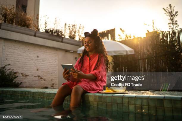 girl sitting by the pool using digital tablet at home - garden ipad stock pictures, royalty-free photos & images