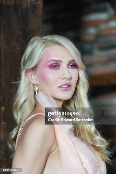 Model wears a beige tulle V-neck / tank-top / short dress, a gold with white and purple rhinestones pendant earring, during the Bisoulovely...