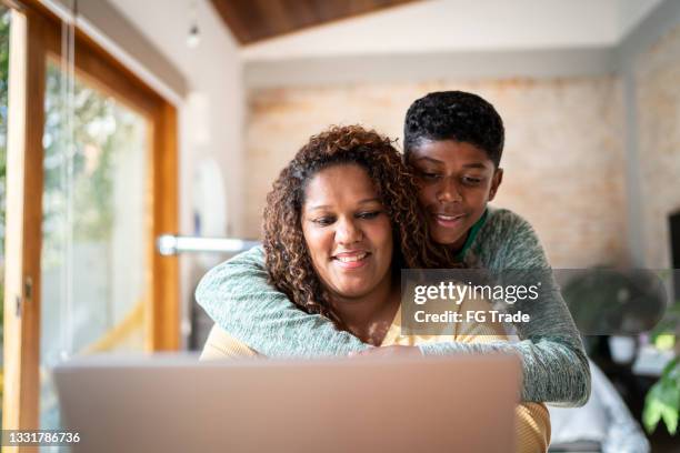 teenager son embracing working mother at home - mother son home stock pictures, royalty-free photos & images