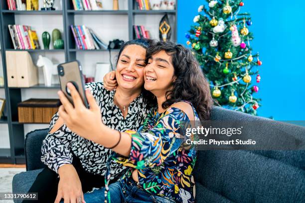 smiling middle eastern mother and daughtertaking selfie on smartphone at home - arab mother and daughter taking selfie imagens e fotografias de stock