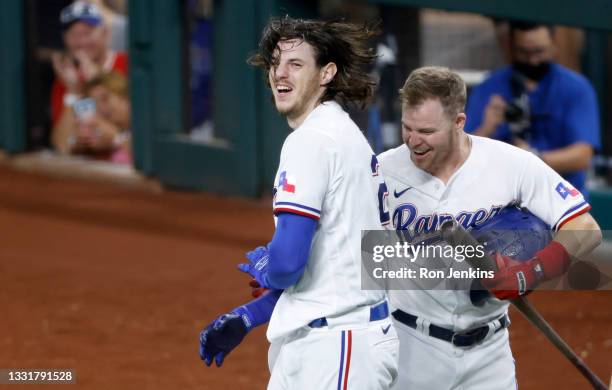 Jonah Heim of the Texas Rangers ""celebrates with teammate Brock Holt after hitting a two-run walk off home run to defeat Seattle Mariners 5-4 in ten...