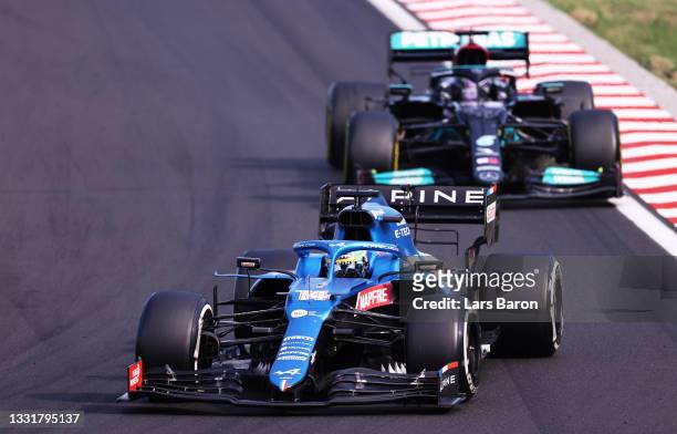 Fernando Alonso of Spain driving the Alpine A521 Renault leads Lewis Hamilton of Great Britain driving the Mercedes AMG Petronas F1 Team Mercedes W12...
