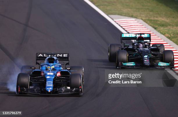 Fernando Alonso of Spain driving the Alpine A521 Renault locks a wheel under braking as he defends from Lewis Hamilton of Great Britain driving the...