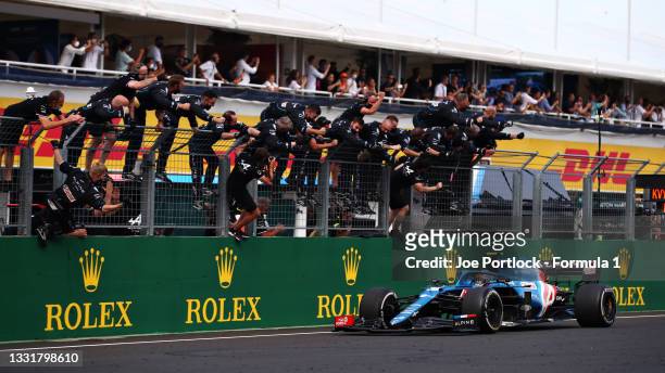 Race winner Esteban Ocon of France driving the Alpine A521 Renault passes his team celebrating on the pitwall during the F1 Grand Prix of Hungary at...