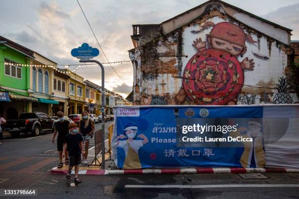 Sandbox travelers pass a sign reminding people to wear masks in Phuket Old Town on August 01, 2021 in Phuket, Thailand. Phuket Town remains a...