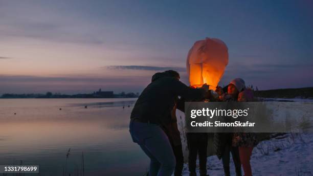 family examining burning sky lantern - chinese father and son snow stock pictures, royalty-free photos & images