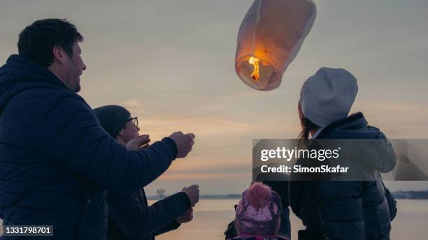 familie, die brennende himmelslaterne freigibt - chinese lantern stock-fotos und bilder