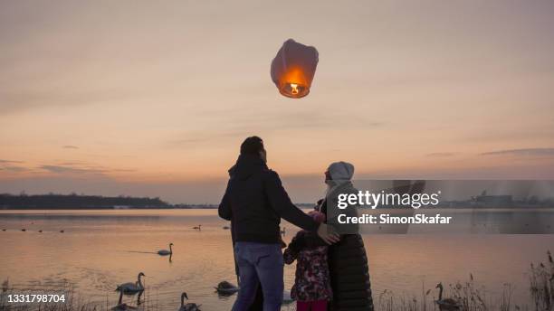 famiglia ammira lanterna del cielo dalla riva del fiume - chinese lantern foto e immagini stock