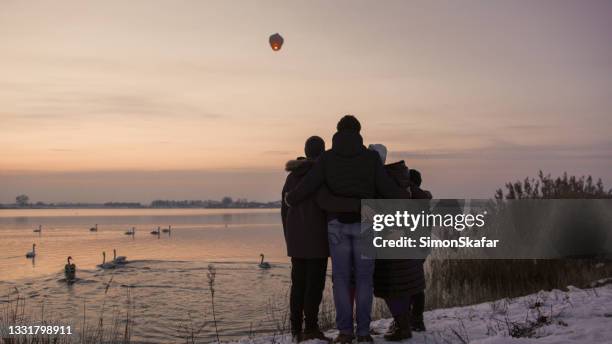 familie bewundert himmelslaterne vom flussufer - chinese lantern festival stock-fotos und bilder