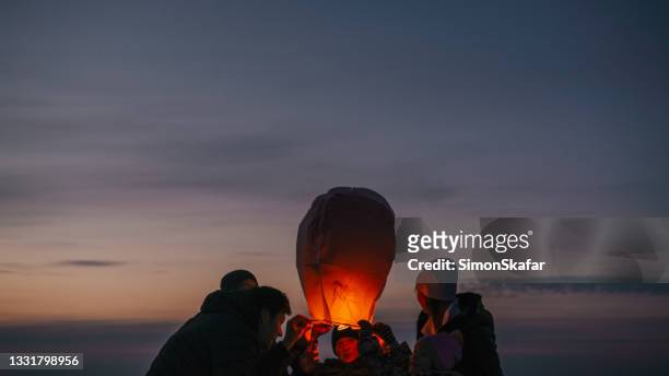 famiglia che rilascia lanterna del cielo in fiamme - lanterna foto e immagini stock