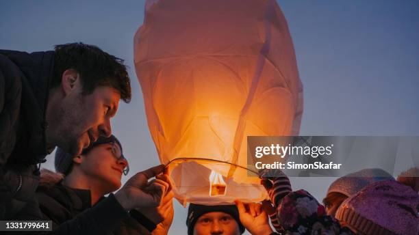 family releasing burning sky lantern - releasing stock pictures, royalty-free photos & images