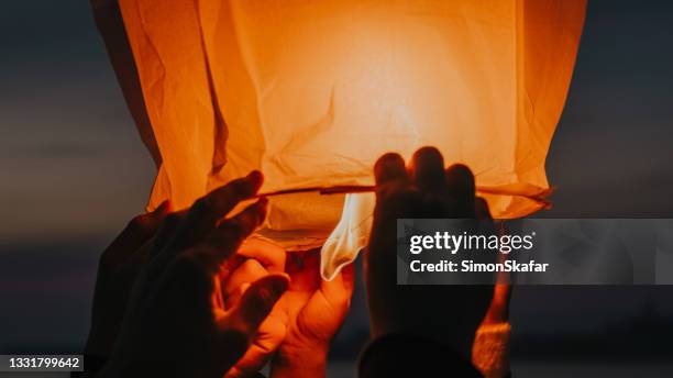 manos que sueltan la linterna del cielo en llamas - chinese lantern fotografías e imágenes de stock