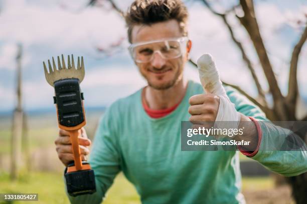 man showing damaged thumbs up while holding electric trimmer - bandaged thumb stock pictures, royalty-free photos & images