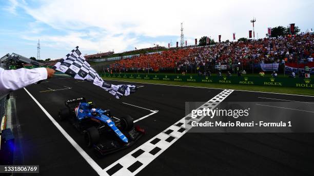 Race winner Esteban Ocon of France driving the Alpine A521 Renault takes the chequered flag during the F1 Grand Prix of Hungary at Hungaroring on...