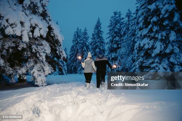 couple walking while holding sparkler on snow covered forest - woman snow outside night stockfoto's en -beelden