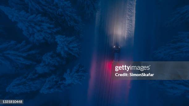 high angle view of car traveling on road in snow covered forest - icy roads stockfoto's en -beelden