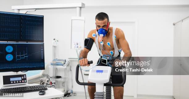 male athlete performing ecg and vo2 test on indoor bicycle - cardio stock pictures, royalty-free photos & images