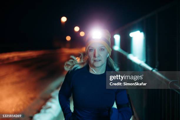 frau joggt nachts auf der straße - stirnlampe stock-fotos und bilder