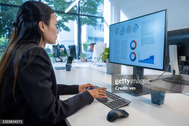 vietnamese woman working on her computer in a shared office - financial analyst 個照片及圖片檔