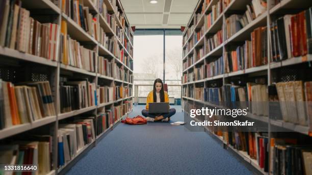 teenage girl using laptop in library - choice student stockfoto's en -beelden