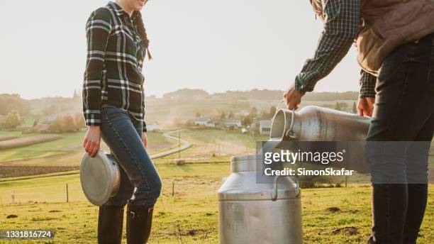 farmer pouring raw milk into other container - rauwe melk stockfoto's en -beelden