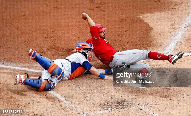 Eugenio Suarez of the Cincinnati Reds is tagged out at the plate by Tomas Nido of the New York Mets during the third inning at Citi Field on August...