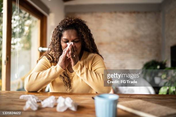 sick mature woman blowing nose at home - blocked nose stock pictures, royalty-free photos & images