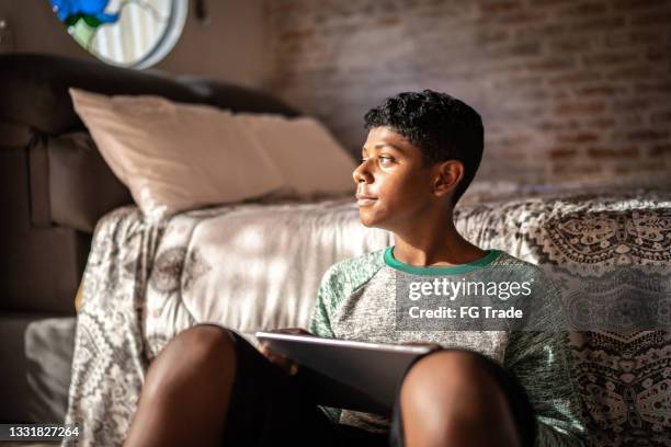 teenager boy using digital tablet and contemplating at home - boy wondering stock pictures, royalty-free photos & images