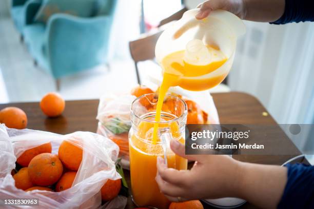 child squeezing orange and making juice at home - family orange juice stockfoto's en -beelden