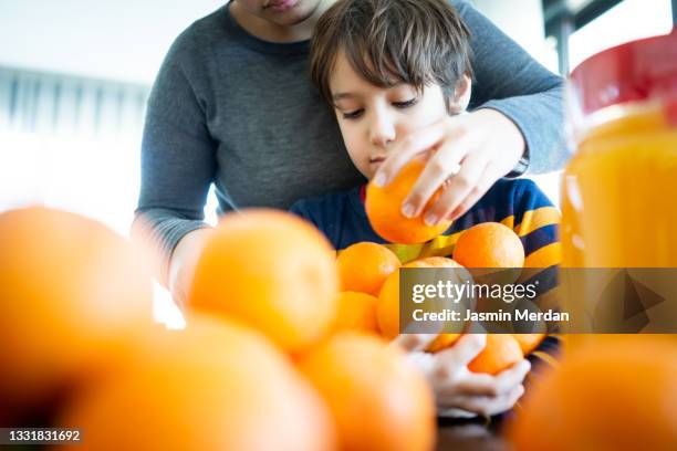 child squeezing orange and making juice at home - family orange juice stockfoto's en -beelden