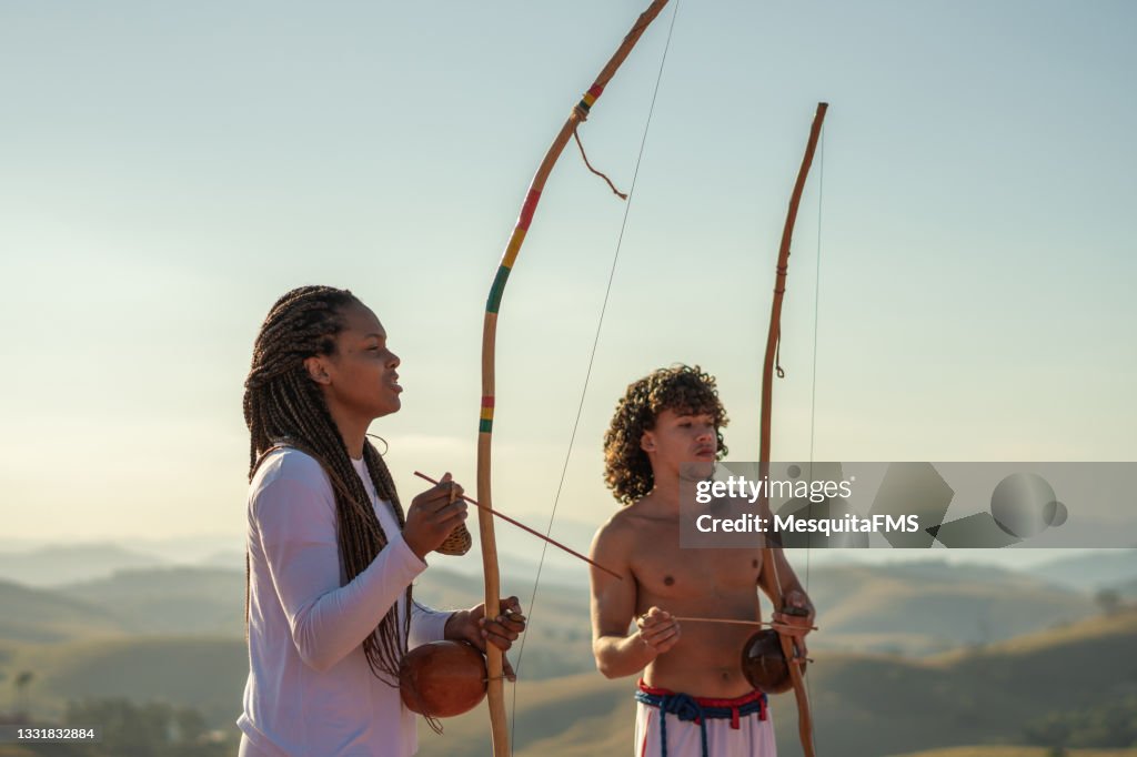 Couple playing berimbau outdoors