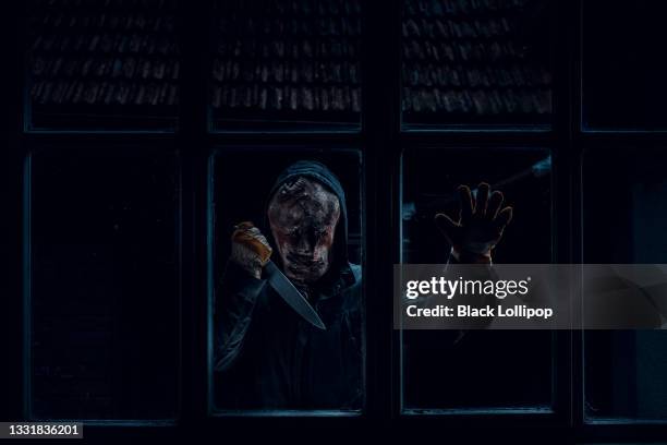中を見て窓の後ろに立っているナイフを持つ怖い男。 - horror movie ストックフォトと画像