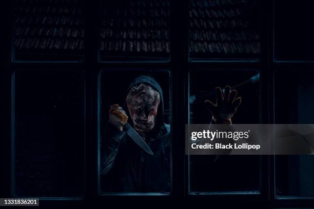 scary man with a knife standing behind the window looking inside. - lollipop man stockfoto's en -beelden