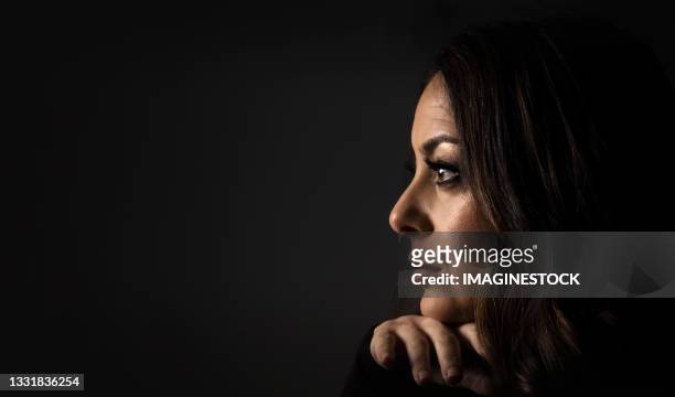 profile portrait of beautiful woman on her hand on a dark background - portrait blurred background stockfoto's en -beelden