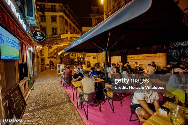 Patrons sit at sidewalk tables of the Liverpool Bar in Pink Street, Cais do Sodre, on the day when traffic restrictions end after 11pm, commerce,...