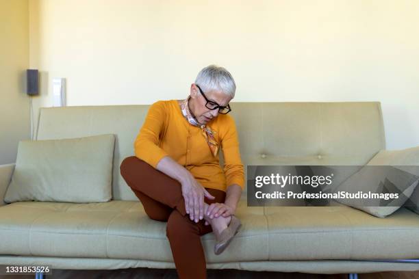 la mujer mayor está luchando con dolor duro en su muñeca de la pierna. - female foot models fotografías e imágenes de stock