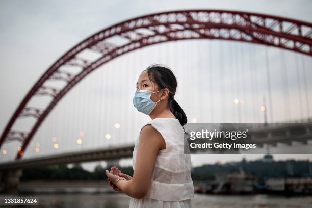 Woman wears a mask near the Han River on August 1, 2021 in Wuhan, Hubei Province, China. The local meteorological bureau issued a high temperature...