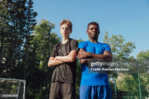 black male soccer coach stands shoulder to shoulder with his student of european appearance. - black lives matter stock pictures, royalty-free photos & images