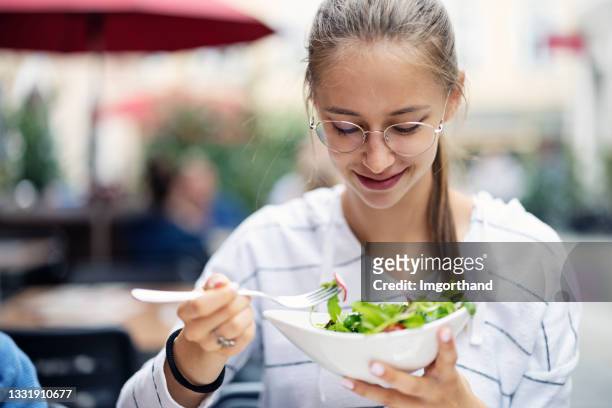 teenage girl eating vegan salad at a restaurant - teenager eating stock pictures, royalty-free photos & images