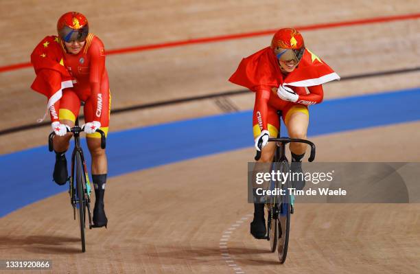 Tianshi Zhong and Shanju Bao of Team China celebrate winning the gold medal while holding the flag of they country after the Women's team sprint...