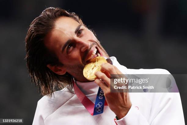 Joint gold medalist Gianmarco Tamberi of Team Italy bites his medal on the podium during the medal ceremony for the Men's High Jump on day ten of the...