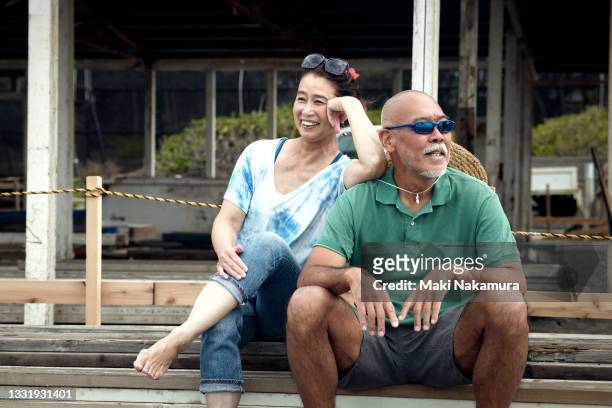 couple relaxing and smiling on the pouch under construction. - older asian couple stock-fotos und bilder