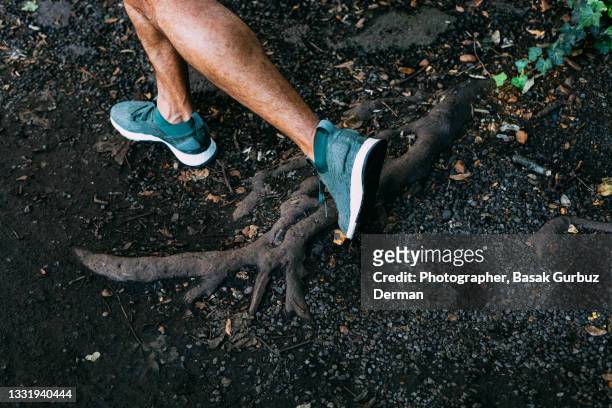 feet of a male runner running in trails, tripping by catching his foot on a tree root - stolpern stock-fotos und bilder