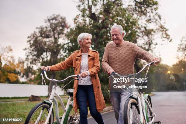 shot of a mature couple taking a bike ride at sunset - couple cycling bildbanksfoton och bilder